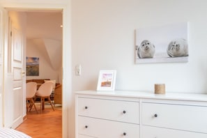 A room with a white dresser, a framed picture, and a wall-mounted artwork of two seals.