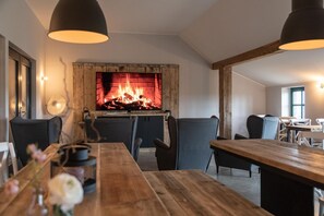 A dining area with a fireplace, wooden furniture, and pendant lighting.