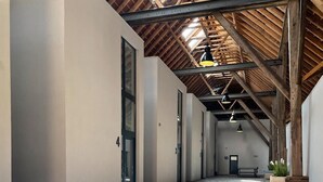 Un pasillo espacioso con techo alto, vigas de madera a la vista y suelo de ladrillo.