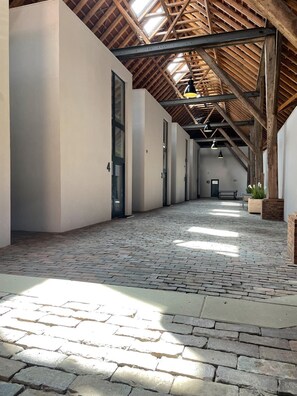 A spacious corridor with a high ceiling, exposed wooden beams, and a brick floor. - Große Fewo im Traumhaften Gulfhof in Meernähe - Gulfhof Dreybült (Dornum)