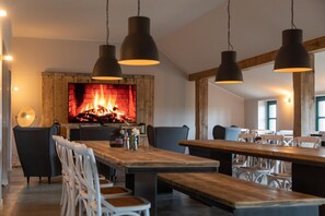 Un comedor con chimenea, mesas y sillas de madera.