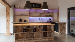 Una cocina rústica con estantes de madera, una isla central, iluminación colgante y un letrero de pizarra.