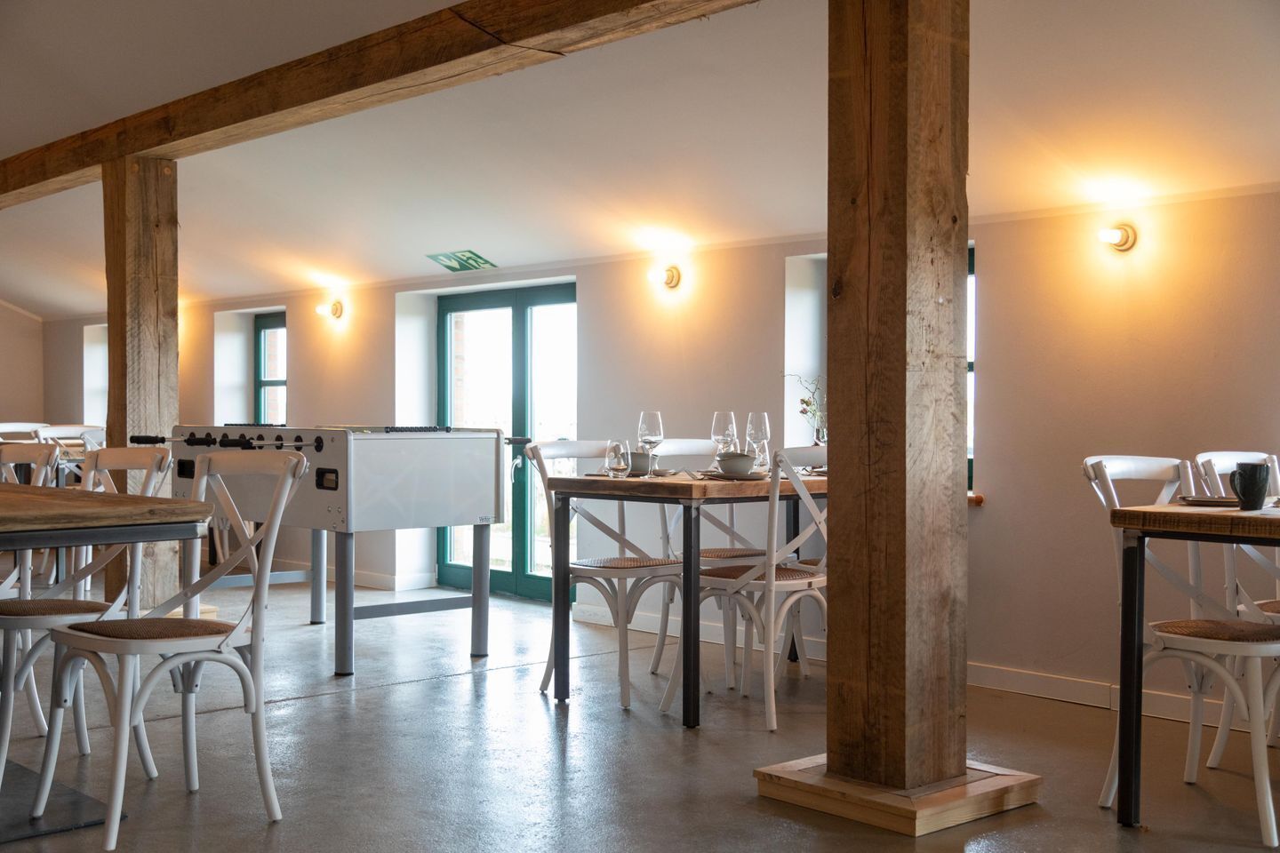A spacious room with tables and chairs, wooden beams, and a whiteboard.