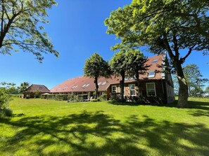 A large building with a red-tiled roof, surrounded by a well-maintained lawn and trees.