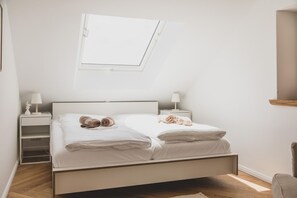 A bedroom with a bed, two bedside tables, a nightstand, a window, and a chair.