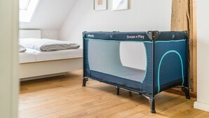 A room with a loft bed, a small trampoline, and a wooden floor.