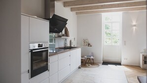 A modern kitchen with white cabinetry, a built-in oven, and a large window providing natural light.