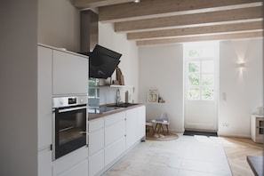 A modern kitchen with white cabinetry, a built-in oven, and a large window providing natural light.