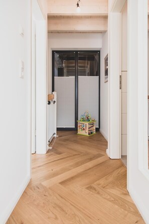 A hallway with wooden flooring, a radiator, and a toy box. - Traumhafte Fewo mit Terrasse im Historischen Hof - Gulfhof Boomgaarden (Krummhörn)