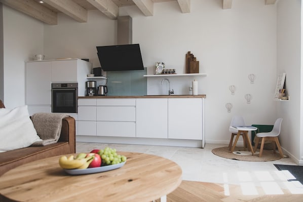 A modern kitchen with white cabinets, a black range hood, and a wooden countertop.