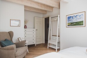 Quarto com cama, poltrona, penteadeira, guarda-roupa e cadeira suspensa.