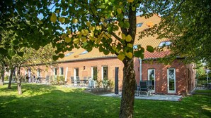 A brick building with a tiled roof, outdoor seating, and a well-maintained lawn.