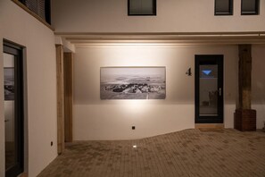 A hallway with a black and white photograph on the wall, a door with a glass panel, and a brick floor. - Moderne und Gemütliche Fewo "gerjet" - Gulfhof Boomgaarden (Krummhörn)