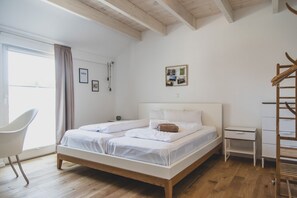 A bedroom with a wooden bed, a white chair, a small bedside table, and a wooden ladder. - Moderne und Gemütliche Fewo "gerjet" - Gulfhof Boomgaarden (Krummhörn)