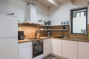 A modern kitchen with white cabinets, a wooden countertop, a built-in oven, and a window with a view. - Moderne und Gemütliche Fewo "gerjet" - Gulfhof Boomgaarden (Krummhörn)