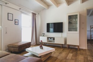 A modern living room with a flat-screen TV, a white cabinet, and a wooden bench. - Moderne und Gemütliche Fewo "gerjet" - Gulfhof Boomgaarden (Krummhörn)