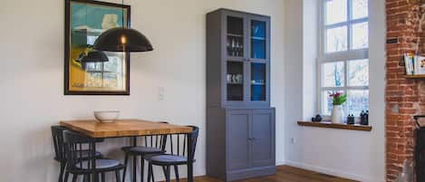 A dining area with a wooden table and black chairs, a gray cabinet with glass doors, and a large window with a view of trees.