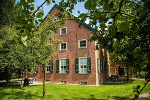 A brick building with multiple windows and a lawn in front.
