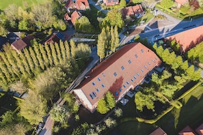 An aerial view of a residential area with a large building featuring a red roof and multiple windows.
