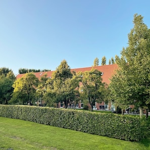 A building with a red roof, surrounded by trees and a well-maintained hedge.