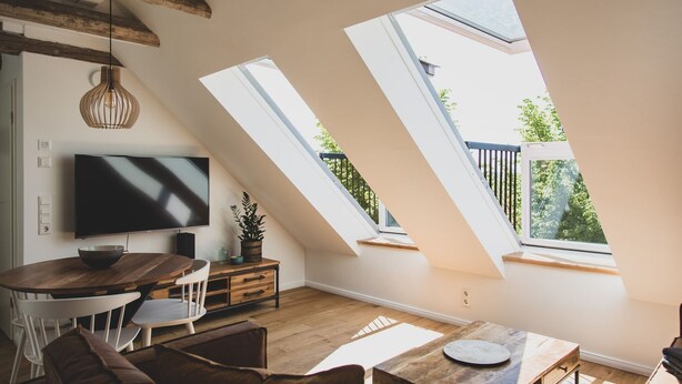 Un loft moderno con una televisión grande, una mesa de comedor de madera y un rincón de estar acogedor.