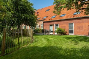 A brick building with a red-tiled roof, a fenced yard, and outdoor seating.