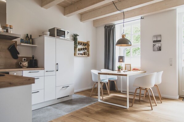 A modern kitchen with white cabinets, a wooden countertop, and a dining area with a table and chairs.