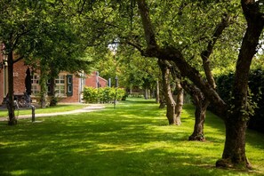 A grassy area with trees and a brick building with windows and a door.