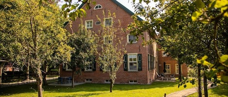 A brick building with a symmetrical facade, multiple windows, and a central entrance.