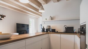 A modern kitchen with white cabinets, a wooden countertop, and stainless steel appliances.