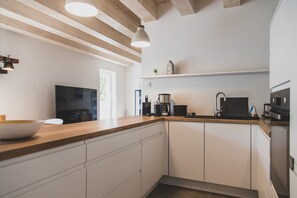 A modern kitchen with white cabinets, a wooden countertop, and stainless steel appliances.