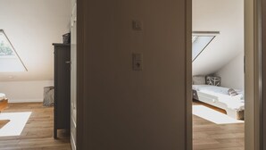 A room with a sloped ceiling, a bed, a small desk, and a window.