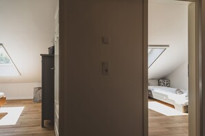 A room with a sloped ceiling, a bed, a small desk, and a window.