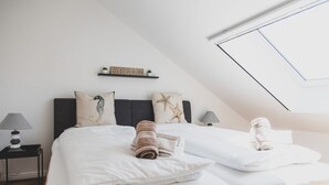 A bedroom with two beds, a skylight, a shelf with a 'DREAM' sign, and a seahorse pillow.