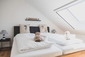 A bedroom with two beds, a skylight, a shelf with a 'DREAM' sign, and a seahorse pillow.