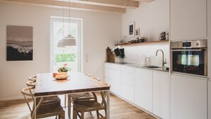 Una cocina moderna con armarios blancos, una mesa de comedor de madera y una lámpara colgante.