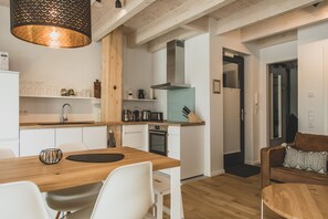 Eine moderne Küche mit Holzschränken, einem Einbauofen und einer Pendelleuchte.