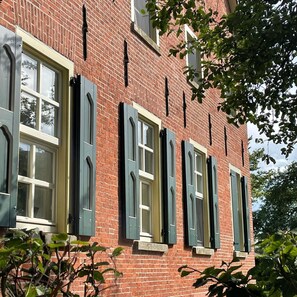 Ein rotes Backsteinhaus mit mehreren Fenstern und Fensterläden.