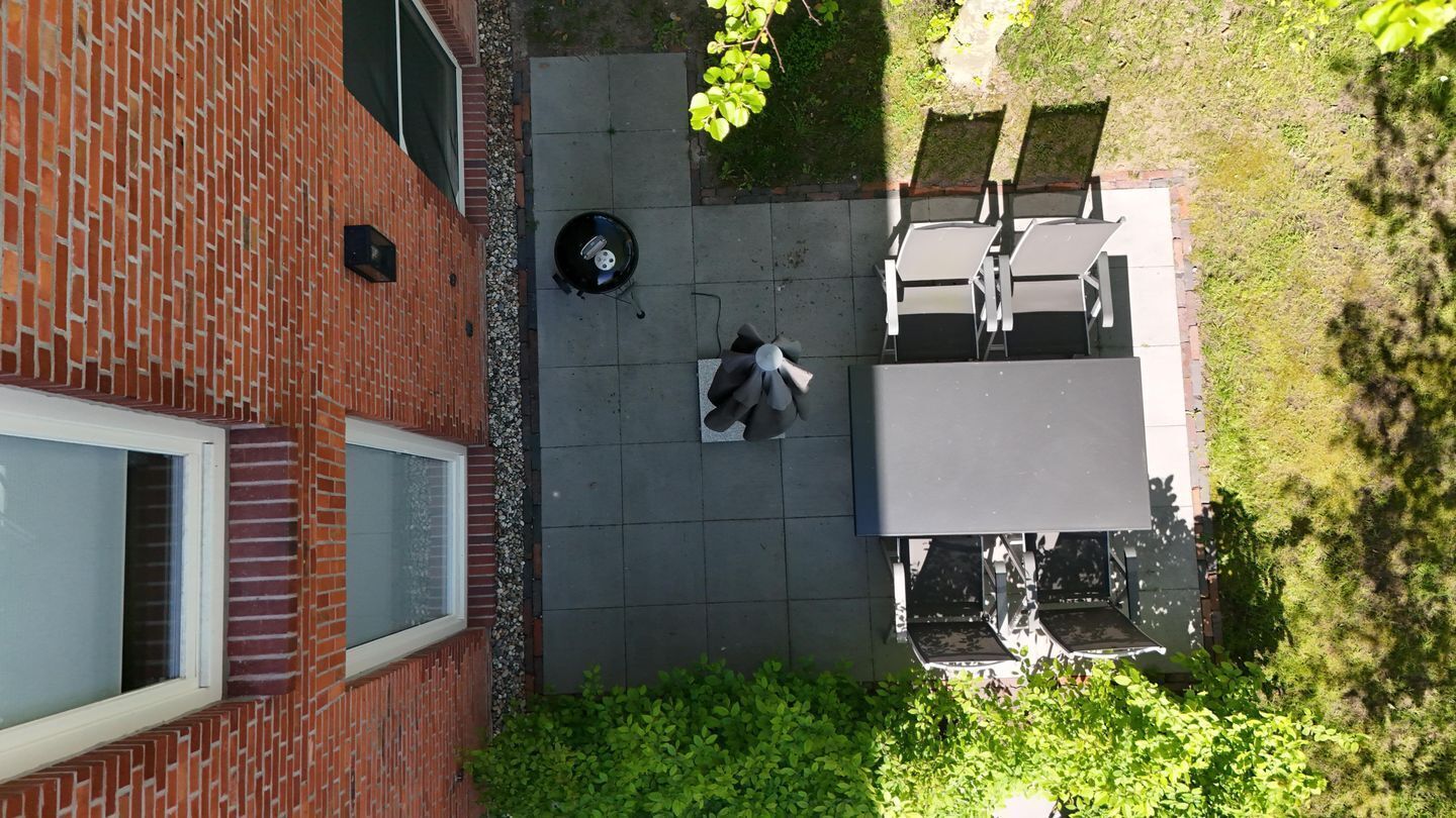 A patio with a grill, outdoor seating, and a brick wall.