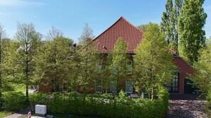 A building with a red-tiled roof, surrounded by lush greenery and trees.