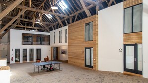 Ein großzügiger Innenbereich mit Tischtennisplatte, Wandverkleidung aus Holz und einer hohen Decke mit freiliegenden Balken.