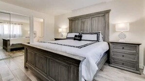 A bedroom with a large bed, a dresser, a mirror, and two bedside lamps. - Renovated Villa in Old Litchfield (Litchfield Park)
