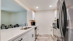 A modern kitchen with white cabinets, a stainless steel refrigerator, and a built-in oven. - Renovated Villa in Old Litchfield (Litchfield Park)