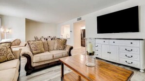A living room with a beige sofa, a wooden coffee table, and a white cabinet with drawers. - Renovated Villa in Old Litchfield (Litchfield Park)