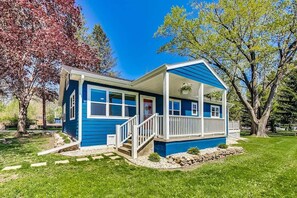 A blue house with a porch, a staircase, and a small garden.