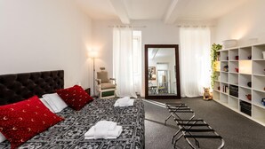 Une chambre d’hôtel avec un grand lit, une chaise, un bureau et une bibliothèque.