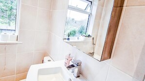 Un baño moderno con lavamanos, inodoro y ventana con vista a zonas verdes.