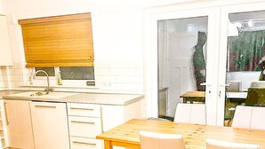 Una cocina con armarios blancos, una mesa de madera y sillas.