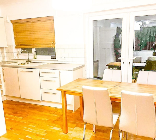 Une cuisine avec des meubles blancs, une table en bois et des chaises.