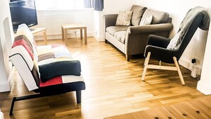Una sala de estar moderna con un sofá, un sillón, una mesa de centro de madera y un televisor.